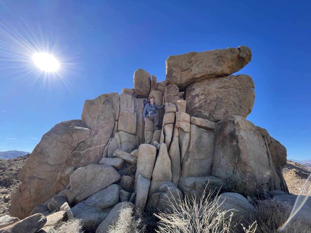 The Places Where We Go visit Joshua Tree. Julie sitting on rock formation.