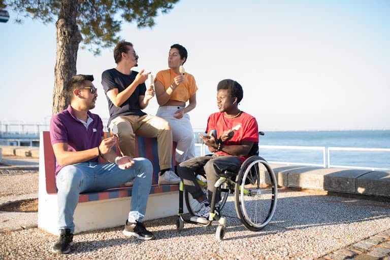 A diverse group of friends sitting outdoors by the sea, enjoying ice cream and socializing.