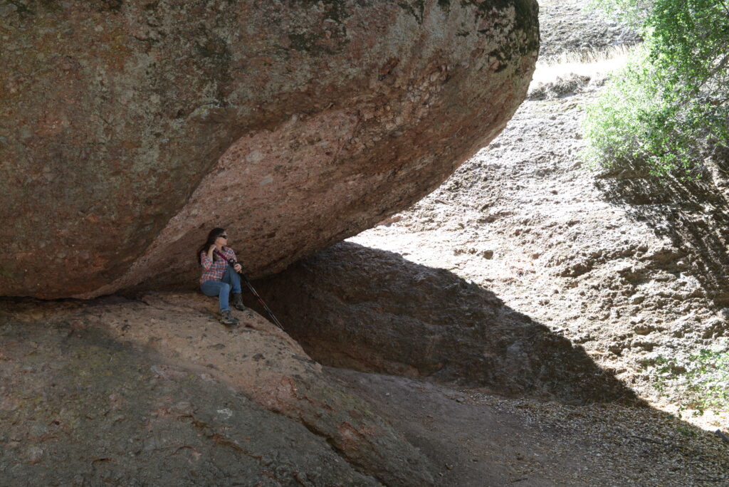 Julie from The Places Where We Go under a large rock at Pinnacles National Park