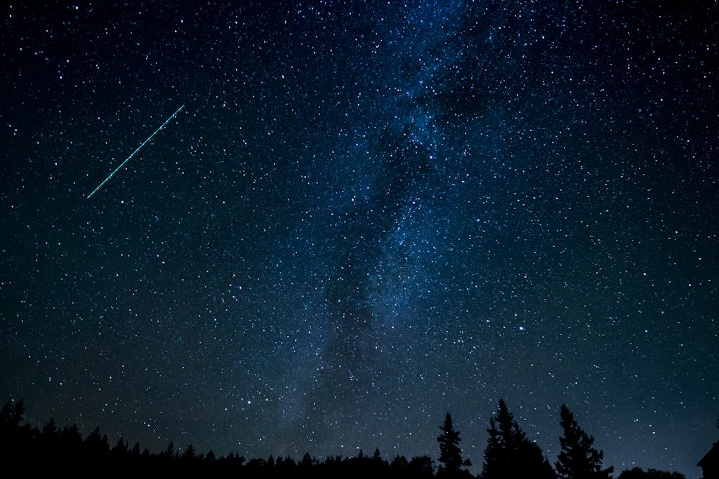 A breathtaking view of the starry night sky with a shooting star streaking across the Milky Way.