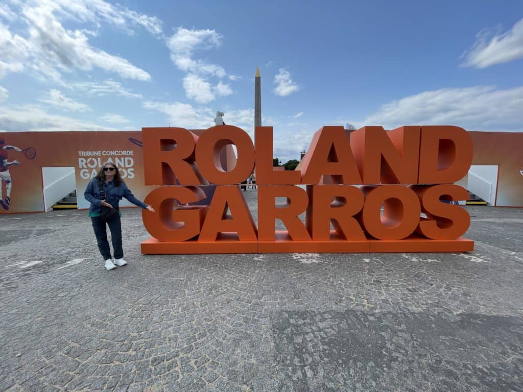 Julie, from The Places Where We Go, standing in front of Roland Garros sign at a French Open viewing event in Paris