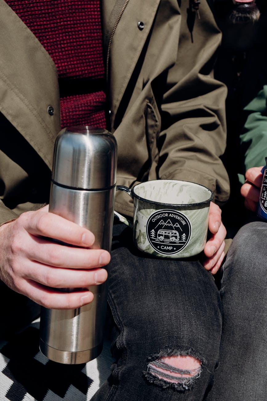 person holding silver and black travel mug
