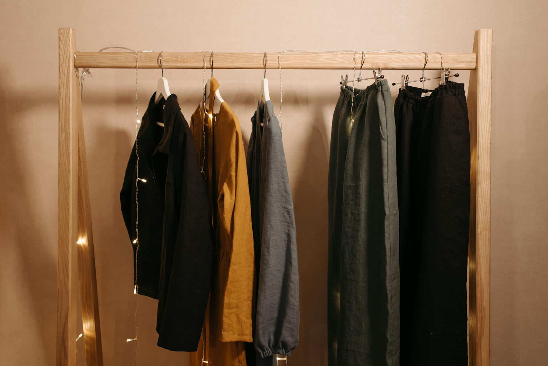 assorted clothes hanging on a wooden rack