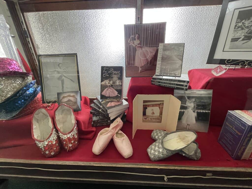 A collection of Marta Becket memorabilia at the Amargosa Opera House Hotel including photos, ballet slippers, books, and performance clothing.