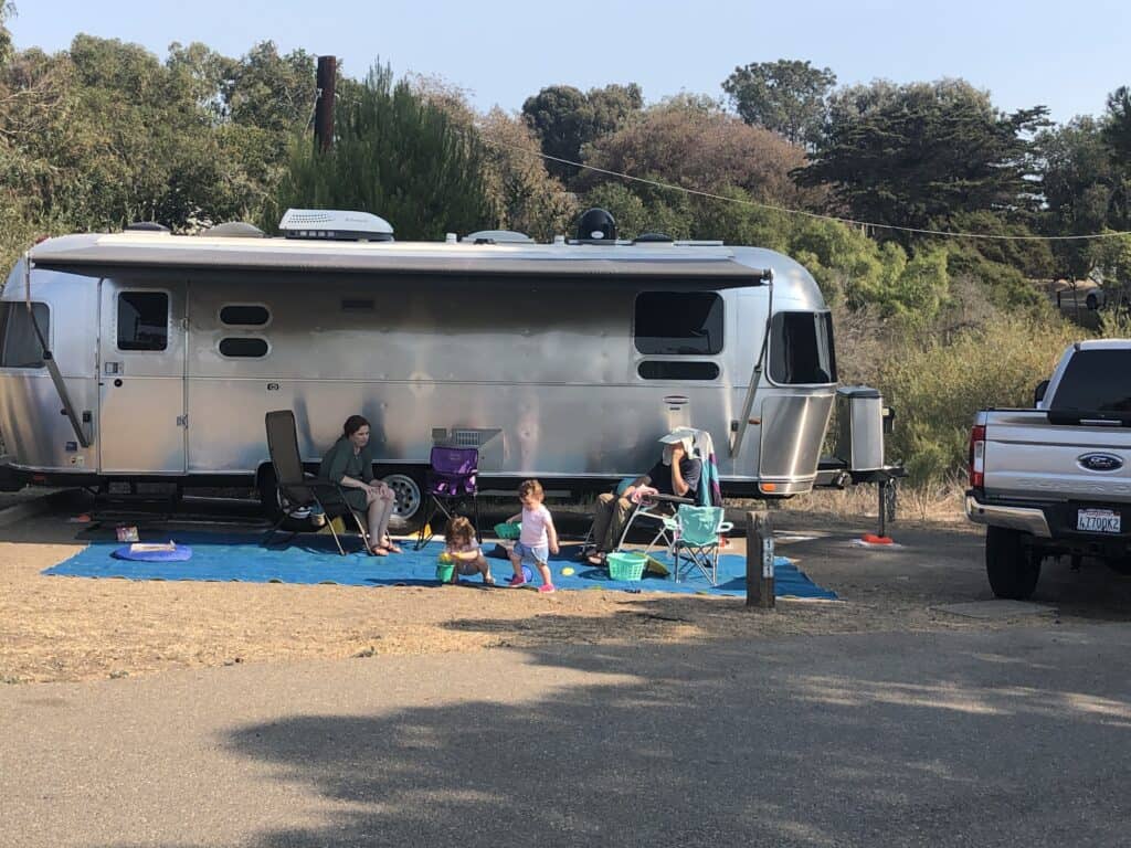 Sitting in front of an Airstream travel trailer at El Capitan State Beach