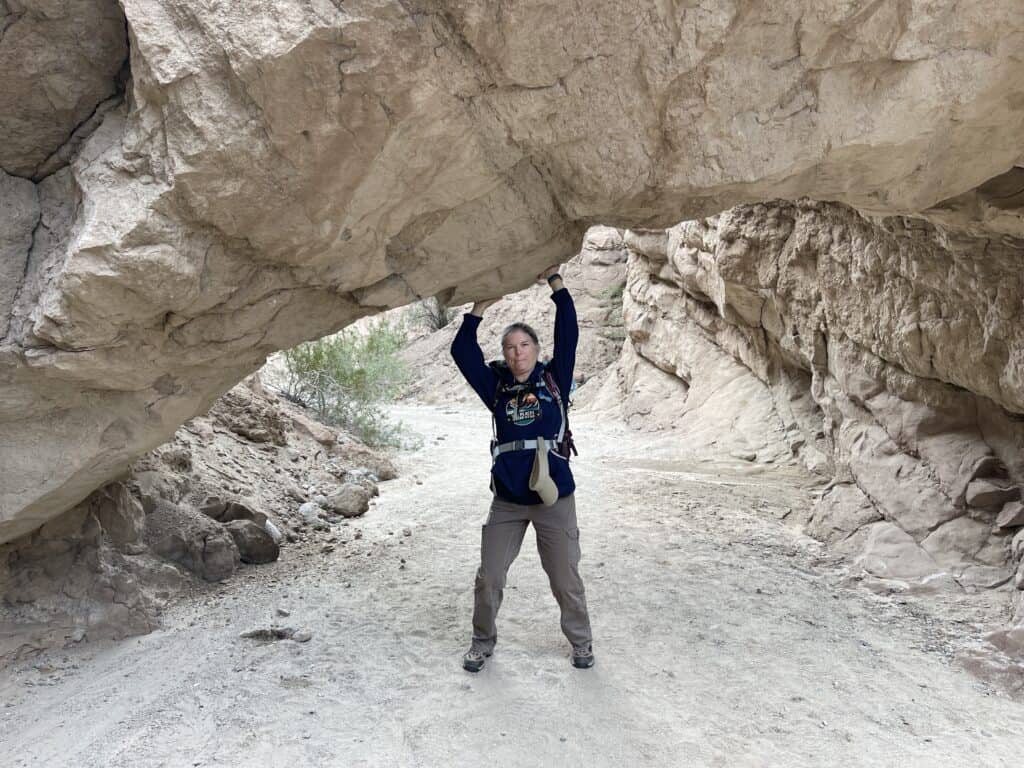 Julie from The Places Where We Go with hands on an arch on the South Fork Palm Wash Canyon trail