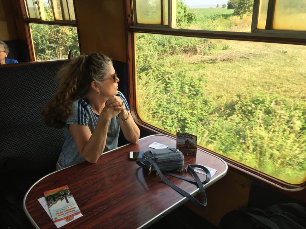 Julie from The Places Where We Go sitting in a booth aboard a West Somerset Railway train car