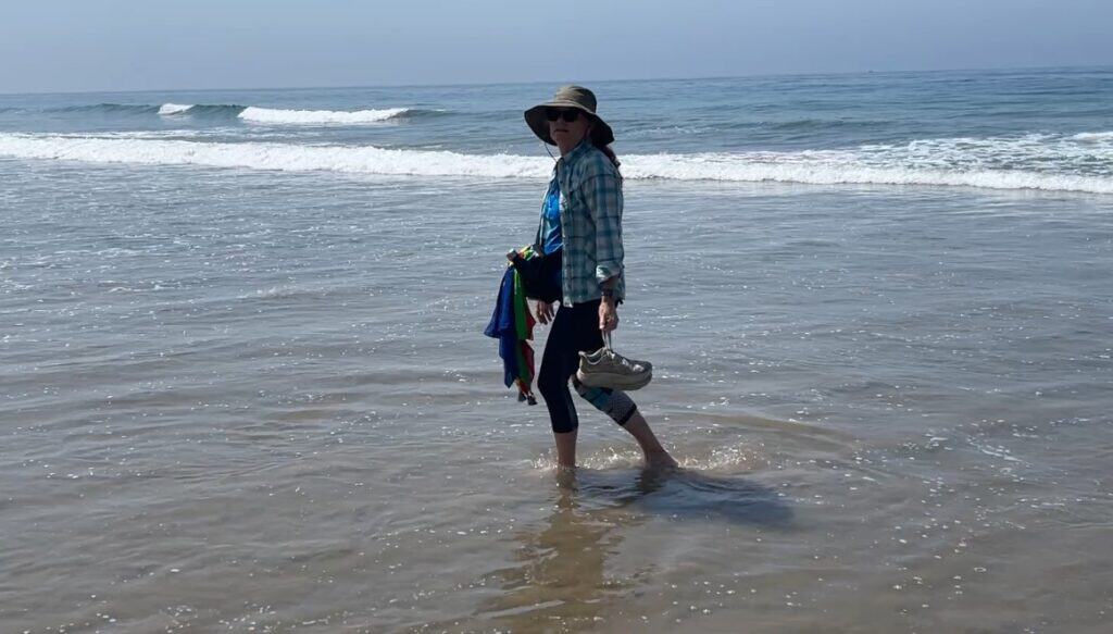 Julie walking on beach during Serra Pilgrimage 2026