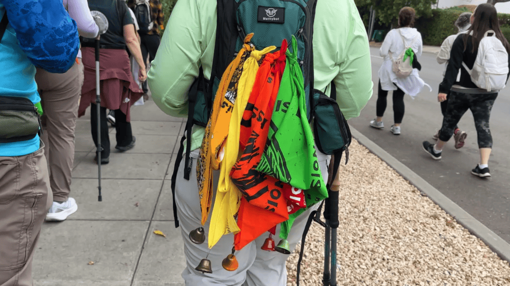 backside of a pilgrimage walker with scarves and bells hanging from a backpack