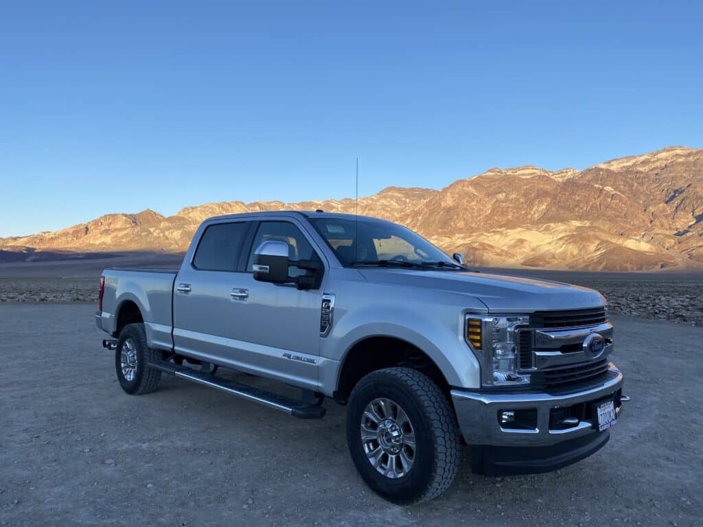 Ford F250 in front of sunlit mountains at Devils Golf Course in Death Valley
